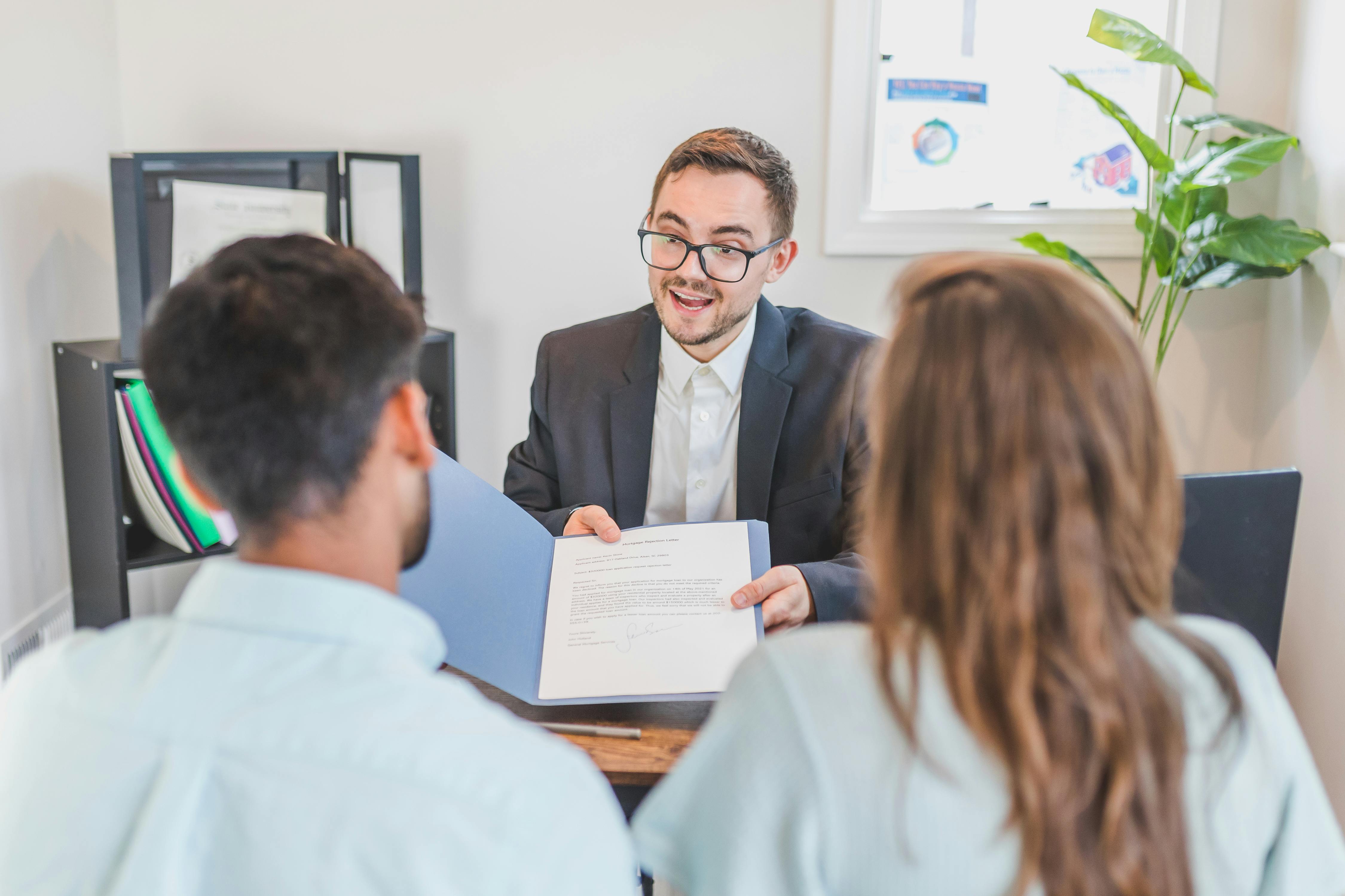 Mortgage broker walking a Florida couple through a refinance contract — the moment to revisit mortgage protection coverage